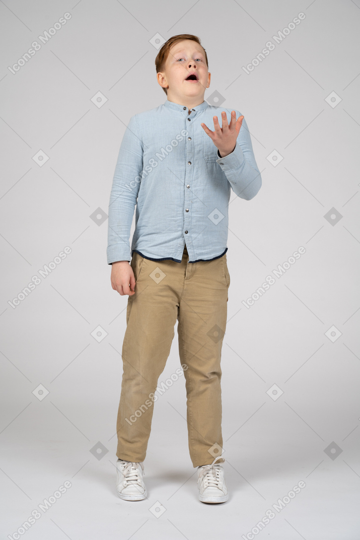 Front view of an emotional boy gesturing and looking at camera