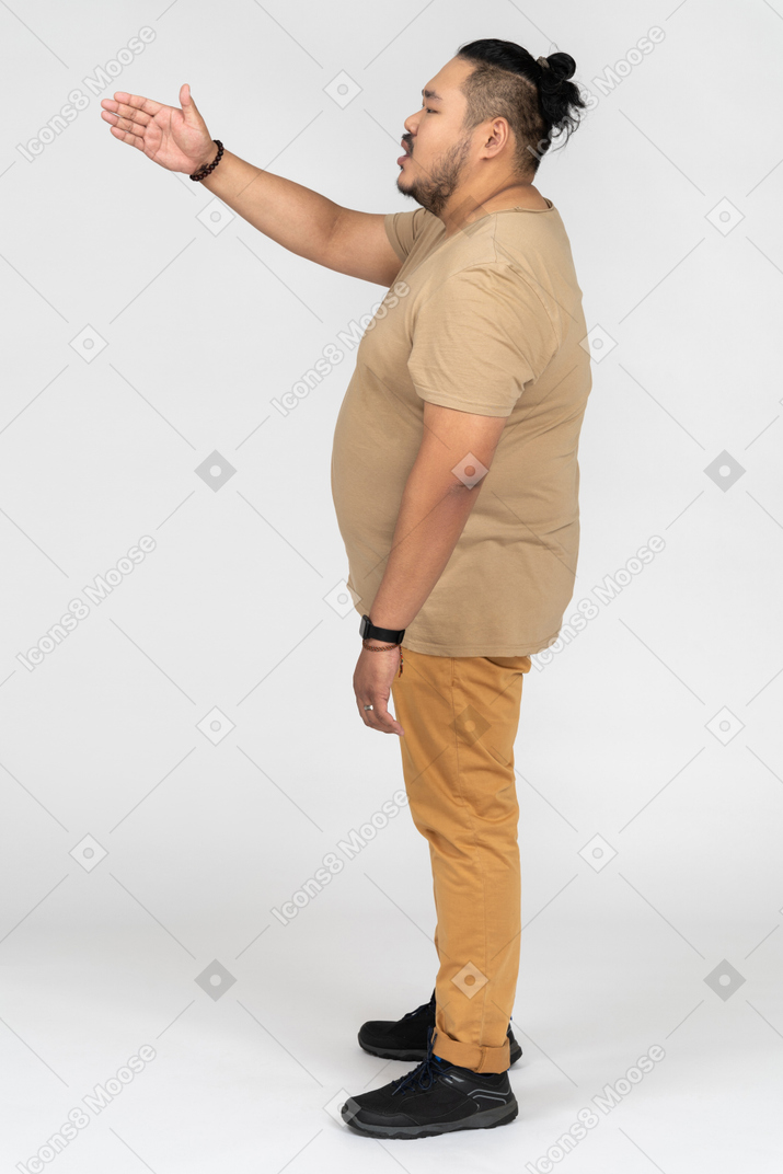 Giovane uomo asiatico gesticolando lateralmente alla telecamera