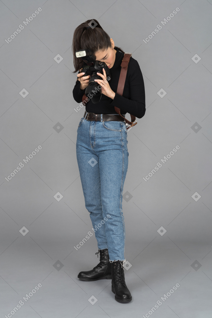 Mujer fotógrafa inclinándose para tomar una foto