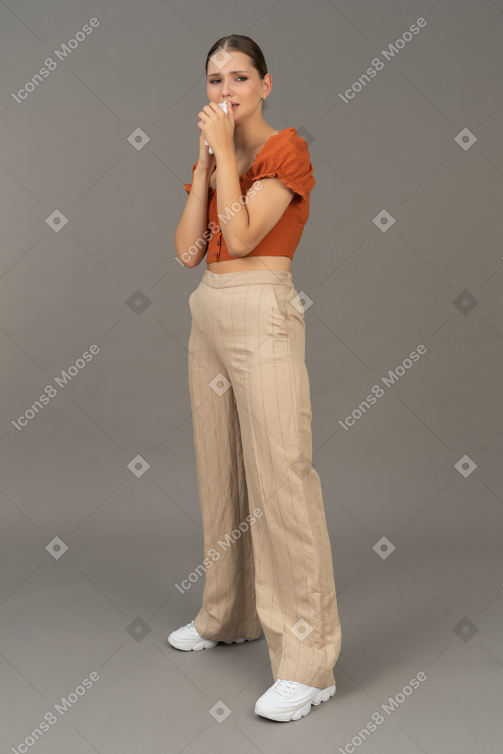 Vista di tre quarti di una giovane donna che piange con un fazzoletto in mano