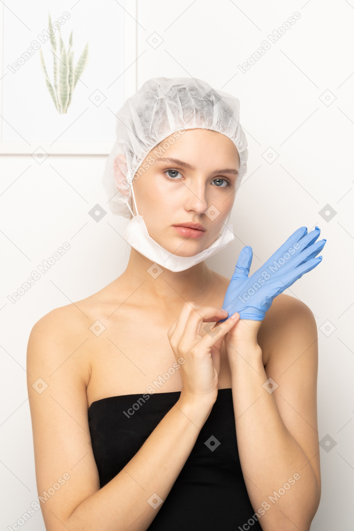 Young woman in scrub cap putting on glove