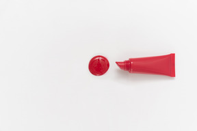 Drop of red lipstick and lipstick bottle on white background