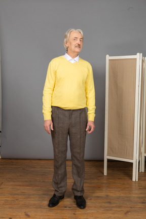Vista frontal de um homem idoso com um pulôver amarelo virando a cabeça