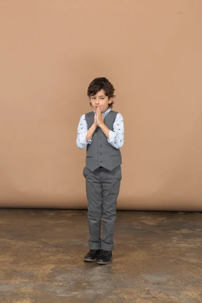 Front view of a boy in grey suit making praying gesture