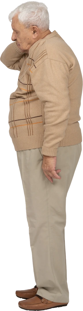 Side view of an old man in casual clothes standing with hand on neck