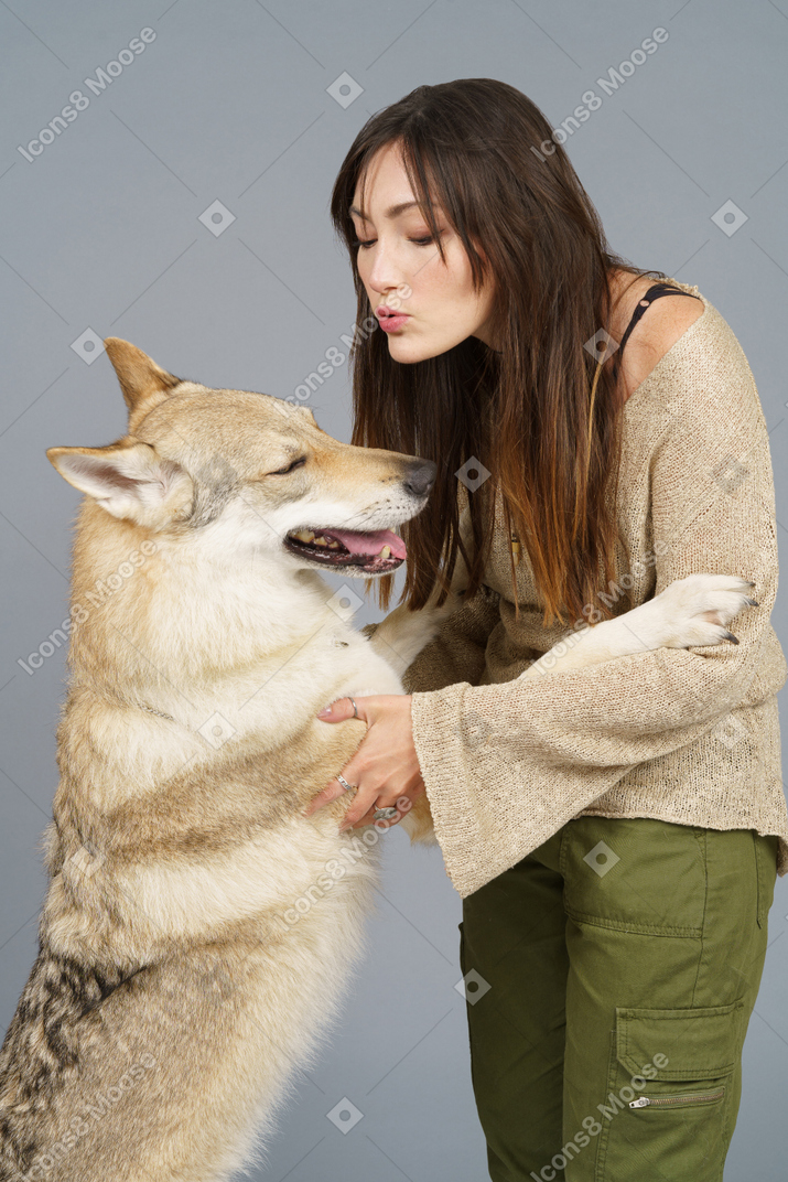 Close-up de uma jovem fêmea abraçando seu cachorro e beijando
