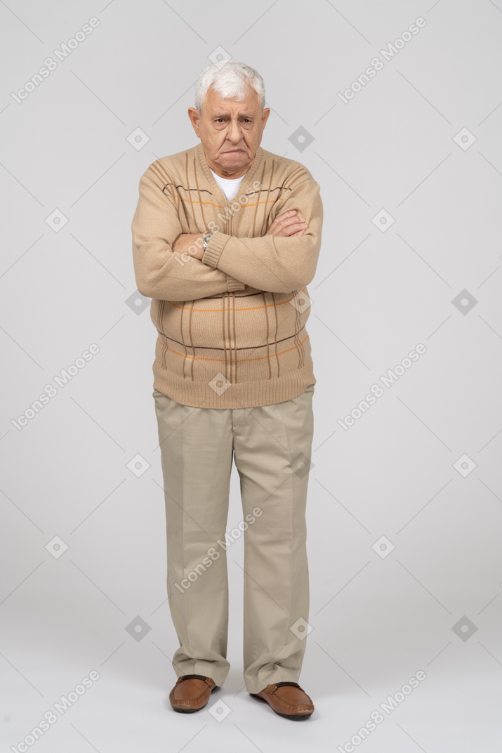 腕を組んで立ってカメラを見ているカジュアルな服装の老人の正面図
