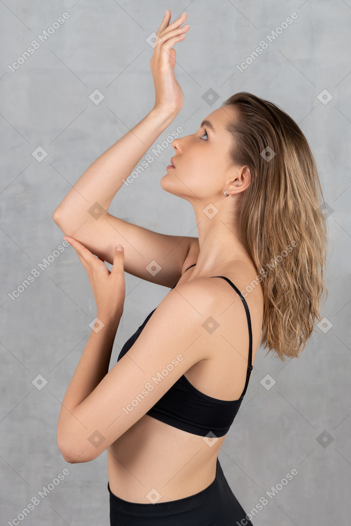 Attraente giovane donna in posa con le braccia alzate