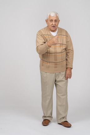 Front view of an old man in casual clothes standing with clenched fist