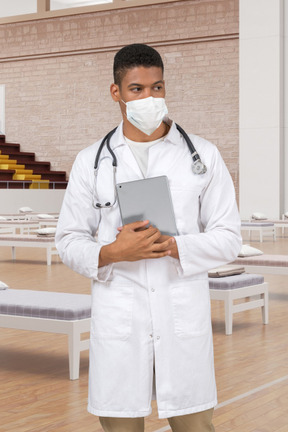 A male doctor in a white lab coat and a face mask