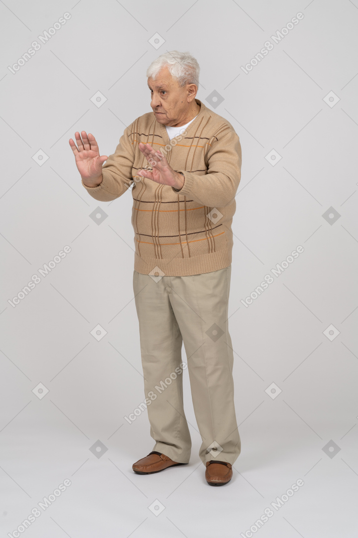 Vista frontal de un anciano con ropa informal que muestra un gesto de parada
