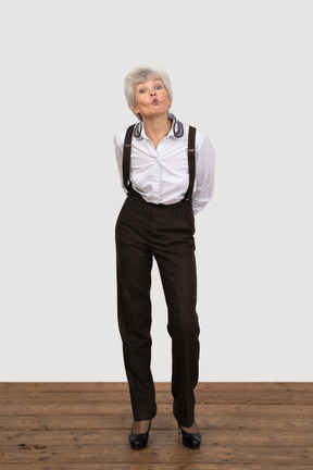 Vista frontal de una anciana haciendo pucheros en ropa de oficina inclinado hacia adelante