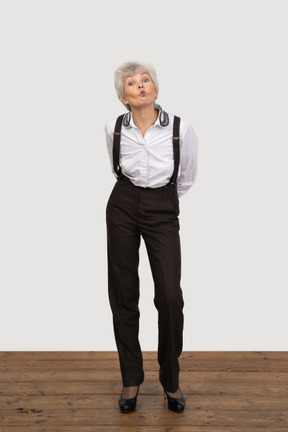 Front view of a pouting old lady in office clothing leaning forward