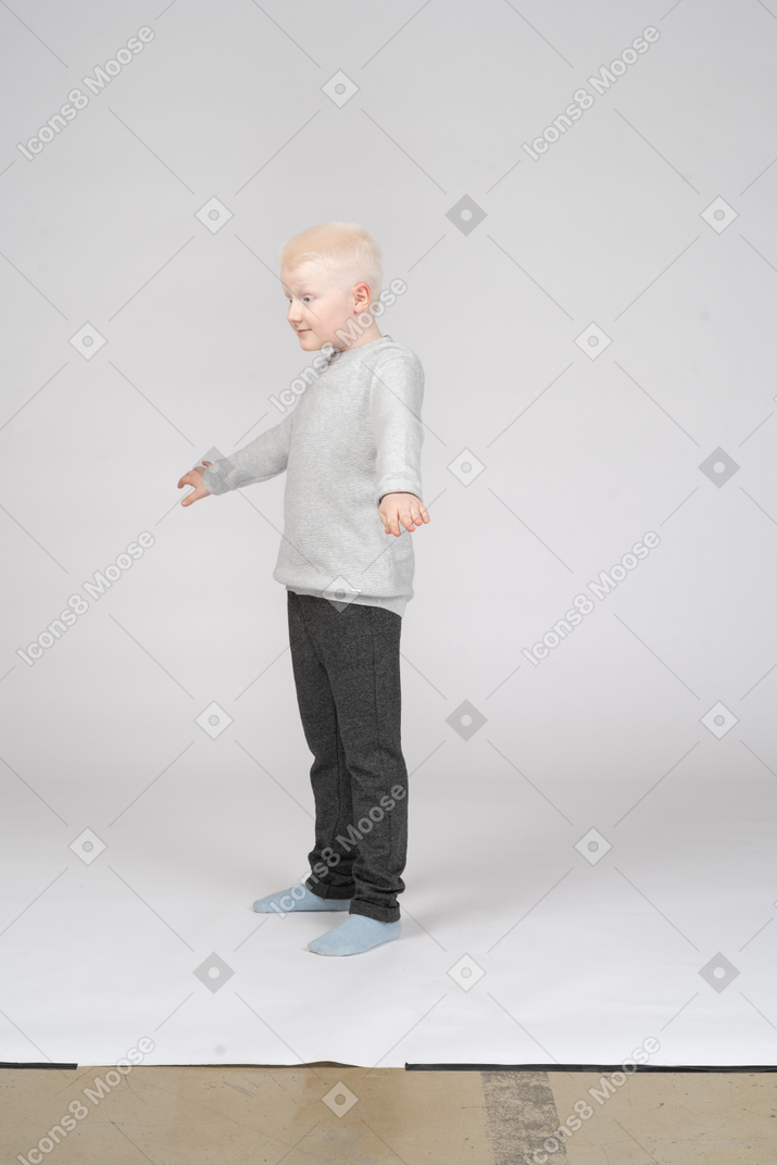 Visão de três quartos de um menino com as mãos ligeiramente levantadas