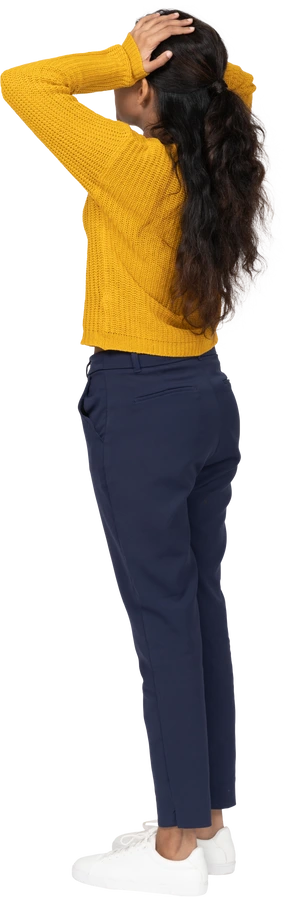 Side view of a girl in casual clothes posing with hands on head