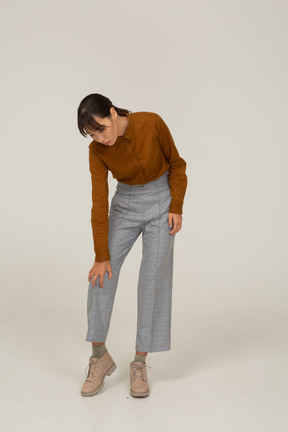 Front view of a young asian female in breeches and blouse leaning forward