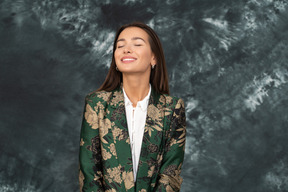 Uma mulher com uma jaqueta verde japonesa sorrindo amplamente com os olhos fechados