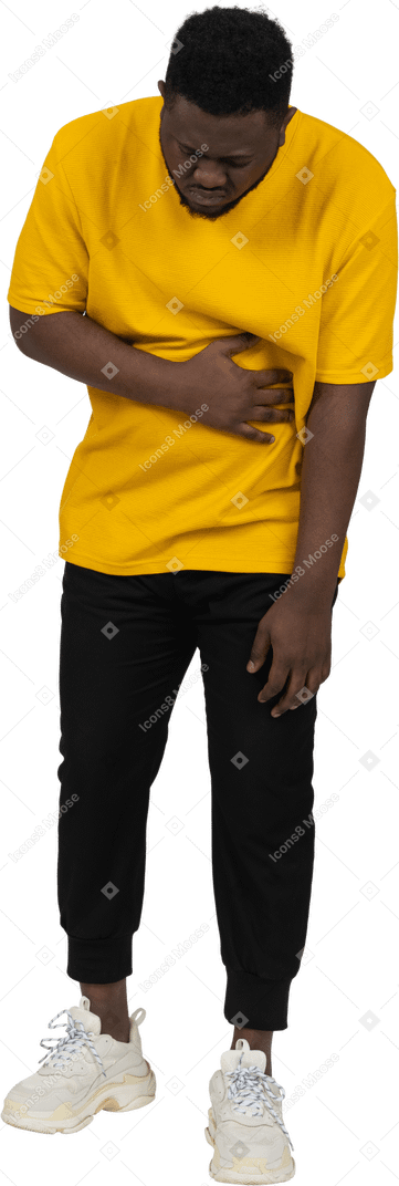 胃に触れる黄色のtシャツを着た若い浅黒い肌の男の正面図