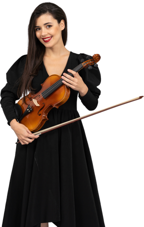 バイオリンを保持している黒いドレスを着た陽気な若い女性のクローズアップ