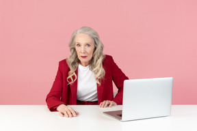 Envelhecido elegante mulher sentada na mesa de trabalho