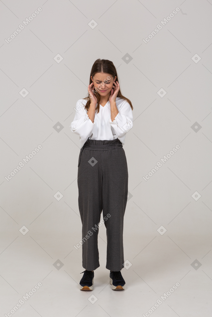 Front view of a young lady in office clothing touching ears