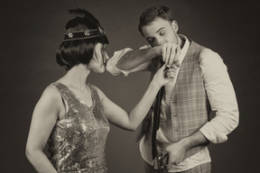 Mujer elegante en tocado viendo a un joven inhalando drogas