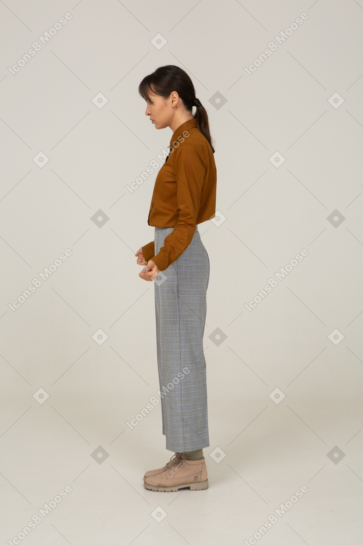 Vue latérale d'une jeune femme asiatique en culotte et chemisier serrant les poings