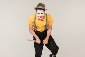 Evil male clown holding knife