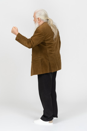 Back view of an old man shaking his fist in the air