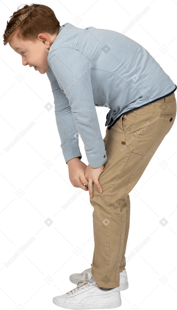 Side view of a boy bending down and touching hurting knee