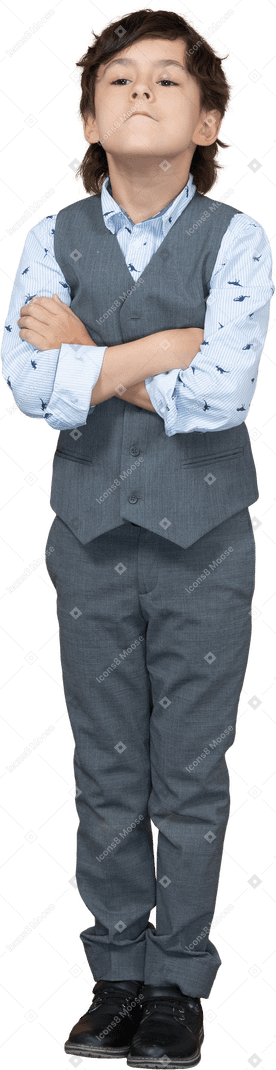 Vista frontal de un niño con traje posando con los brazos cruzados