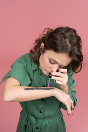 Mujer inhalando polvo negro con paja rosa