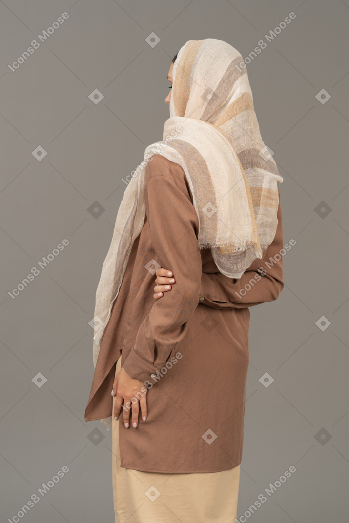 Woman in traditional clothing holding hand behind the back
