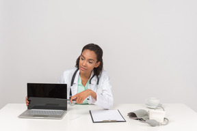 Confiante médico feminino mostrando algo em seu laptop