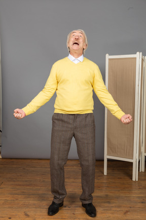 Front view of a screaming old man outspreading hands while looking up