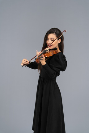 Close-up de uma jovem de vestido preto tocando violino