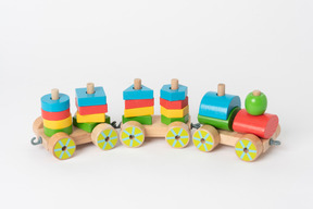 A colorful wooden toy train and geometrical shapes of many colors, lying against a plain white background