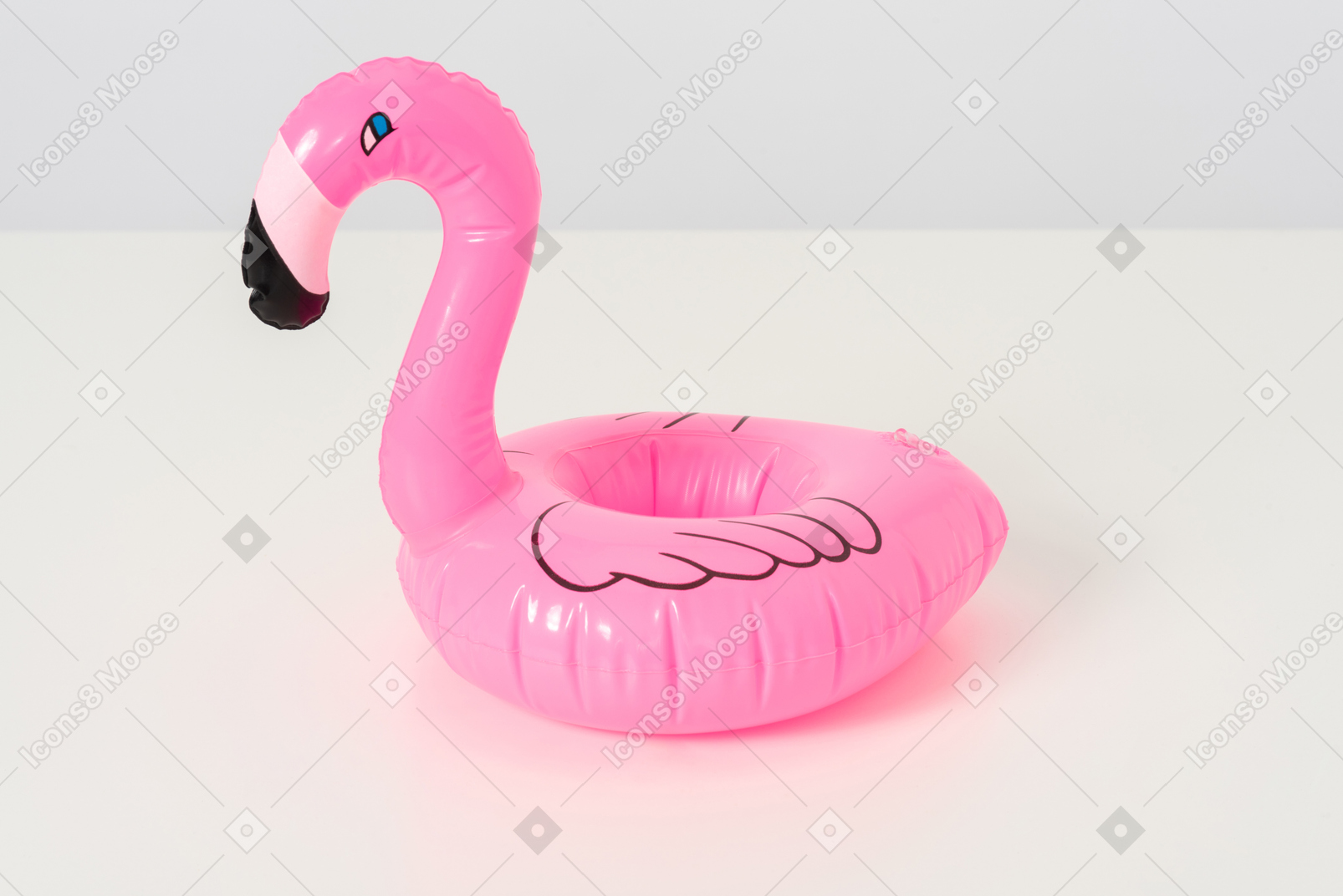 A tiny inflatable pink flamingo looking back slyly at everyone who wants to play with it