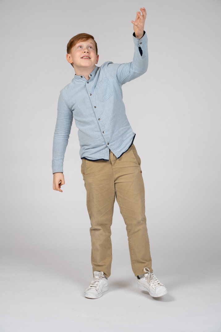 Front view of cute boy pointing up with a hand