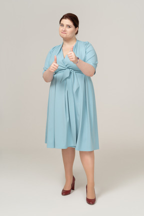 Vista frontal de uma mulher de vestido azul mostrando os polegares para cima