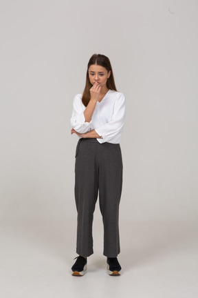 Front view of a worried young lady in office clothing touching face