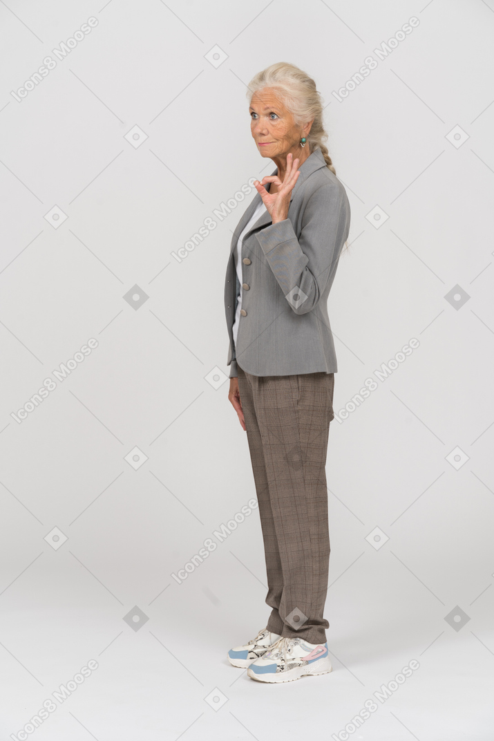 Seitenansicht einer alten dame im anzug, die ein ok-zeichen zeigt
