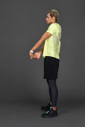 Vista lateral de un joven de piel oscura extendiendo los brazos