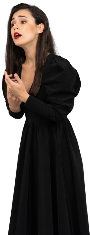 Vista di tre quarti di una giovane donna gesticolante preoccupata in abito nero