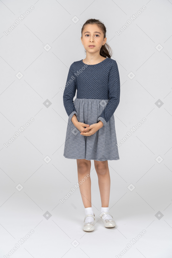 Vista frontal de uma garota de pé com as mãos entrelaçadas parecendo incerta