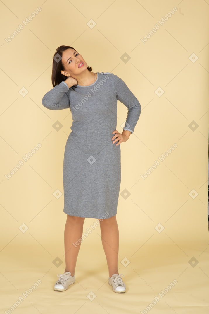 목에 통증이 있는 회색 드레스를 입은 여성의 전면 모습