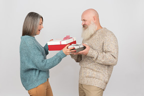 Elegante pareja de ancianos dando regalos el uno al otro