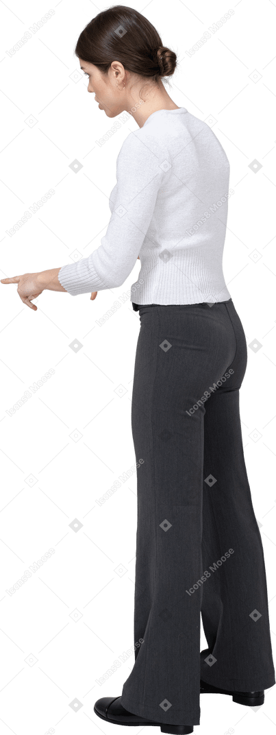 Side view of a young woman in casual clothes pointing with a finger