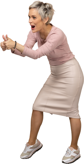 Vista lateral de una mujer feliz en ropa casual mostrando los pulgares para arriba
