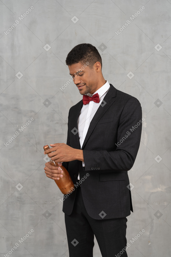 Homem sorridente de terno completo abrindo uma garrafa de champanhe